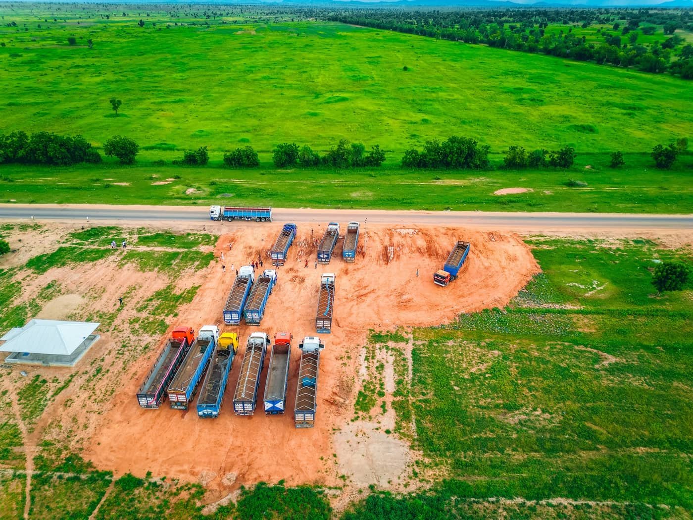 Haulage trucks on the cleared ground — the site is already in working use.